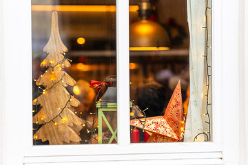 A beautifully decorated window glowing with Christmas motifs and twinkling evening lights creating a warm festive atmosphere outdoors
