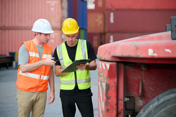 Workers wearing safety gear, inspecting forklift at containers yard