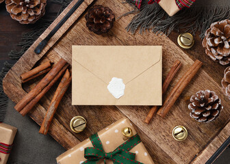 Sealed envelope on rustic wooden tray near Christmas decor top view. Holiday mockup