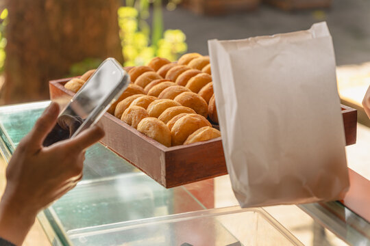 customer paying with smartphone while buying fresh donuts at local bakery stall - Powered by Adobe
