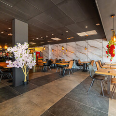 A beautifully designed restaurant interior showcasing a modern and elegant dining area. The space features contemporary furniture, including wooden chairs and tables set with glassware, plates.