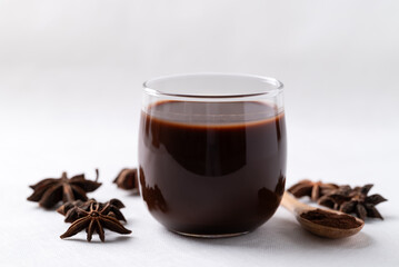 Hot chocolate in glass and star anise on white background