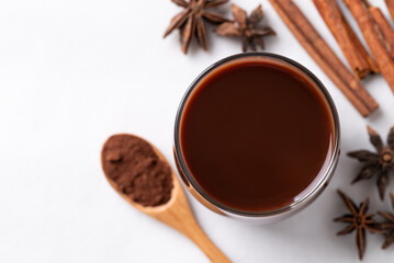 Hot chocolate in glass and star anise and cinnamon sticks on white background, Top view