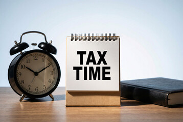 Tax time reminder with alarm clock and planner on wooden desk, finance deadline, payment and accounting concept.
