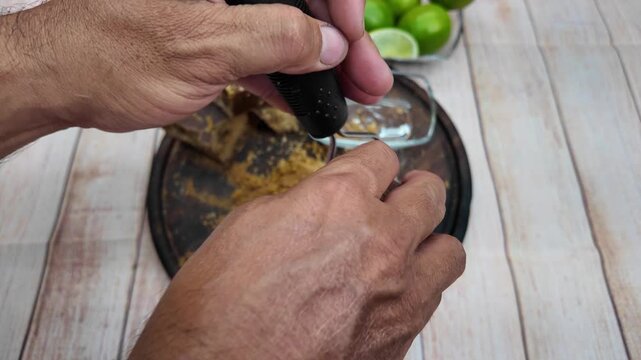 Grating panela by hand on a wooden surface with limes in the background