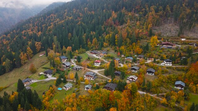 Drone footage of Unken village in Heutal, Austria, with rustic huts and colorful autumn forest on the slopes.