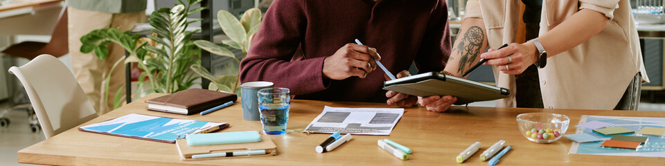 Caucasian young adult woman and Black young adult man collaborating at desk, reviewing documents...