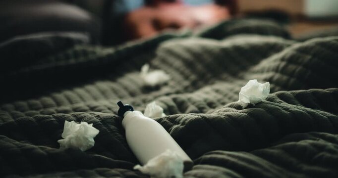 Lotion, tissues and person in bed for temptation, self pleasure and masturbation in home. Night, lubricant and man with arousal for pornography, addiction and paper towel in bedroom of apartment