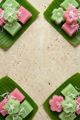 Traditional Thai dessert flat lay of pastel pink and green Khanom Chan layer cakes on banana leaves with coconut topping and copy space on vertical beige stone background for menu design.