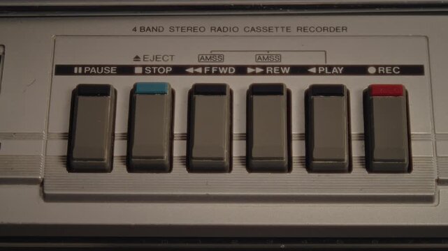 A Man Inserts A Compact Cassette Into A Retro 1985 Boombox While Resting Comfortably On A Sofa, Surrounded By Warm Neon Light And A Cozy Interior That Enhances The Vintage Music Experience