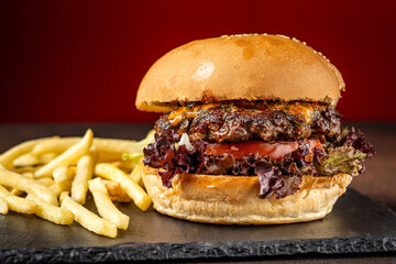 Juicy cheeseburger with fries on slate board