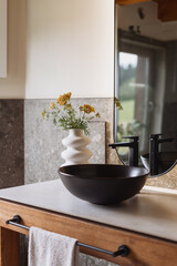 Modern rustic bathroom design featuring a black ceramic washbasin and vase
