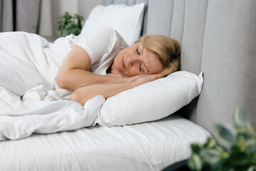 Fototapeta premium Cozy morning in a hotel bedroom with a woman enjoying her peaceful sleep