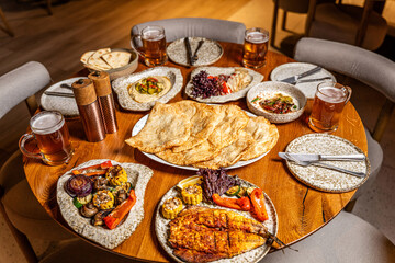 Shared restaurant feast with grilled dishes and beer