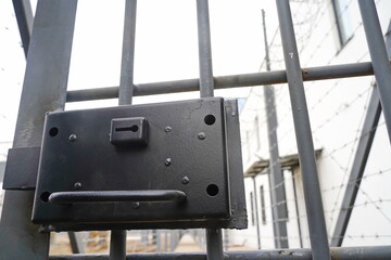 A keyhole in a metal door against a background of barbed wire. Fence.