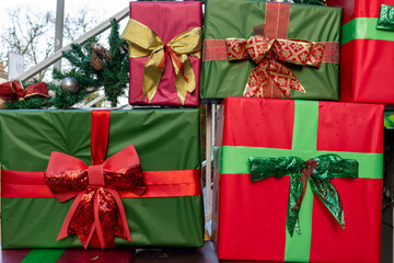 Wrapped Christmas gift boxes with decorative bows in red, green, and gold colors. Outdoor festive display with traditional packaging.