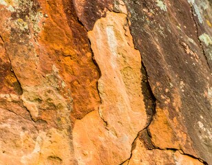 Close-up of layered, weathered rock face with various shades of orange, brown, and rust