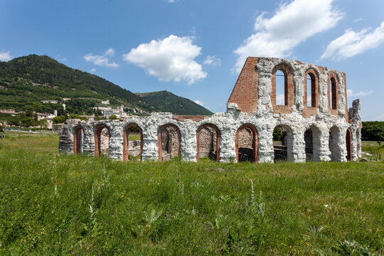 View of the ancient Roman theatre ruins in Gubbio, Umbria&mdash;arched stone structures set in a green landscape.