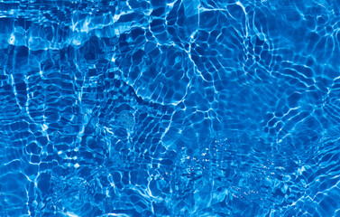 Blue water with ripples on the surface. Defocus blurred transparent blue colored clear calm water surface texture with splashes and bubbles. Water waves with shining pattern texture background.