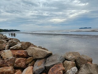Coastal scene with breakwater rocks and low tide sea, suitable for themes related to coastal defense, seascape, tides, tropical beaches, or travel.