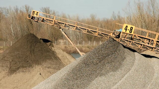 Conveyor belts transport different granulations of building materials, sand and gravel, rock crusher machine at work.