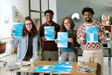 Group of young adult multiethnic men and women standing together holding real estate flyers,...