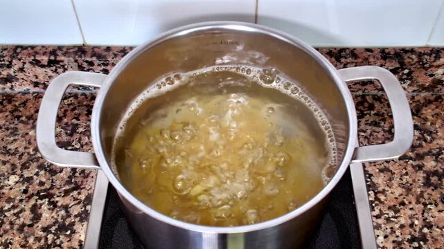 Stainless steel pot with pasta boiling in water on an induction cooktop, a classic preparation representing the heart of Italian cuisine, a cornerstone of the Mediterranean diet