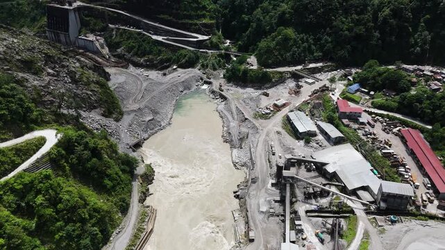 Cinematic aerial footage of a remote construction site in the Himalayas showing the layout of the base camp roads and the river diversion for a clean energy major project.