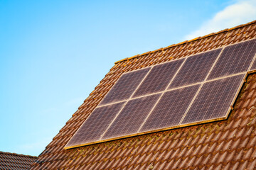 Green energy solar panels on roof. Renewable energy solutions building house in neighborhood. Clean energy, sustainability, eco-friendly technology powered by the sun against light blue sky. 