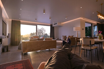 Modern luxury living room interior at sunset. Open-plan space featuring beige sofas, marble dining...