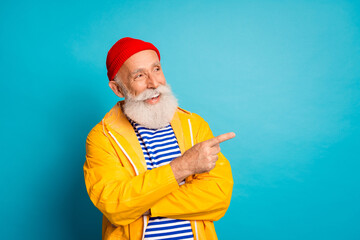 Bearded elderly man in yellow raincoat smiling and pointing against a blue background a retro stylish image perfect for advertising and lifestyle campaigns