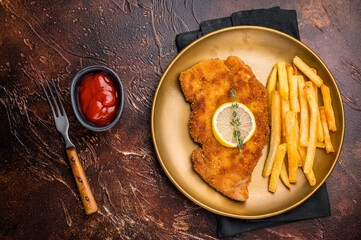 Wiener pork schnitzel steak, breaded meat with french fry on a plate. brown background. top view