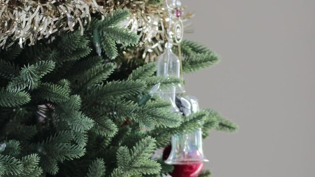 Close up shot of two hands reaching in and removing a Christmas ornament off of a decorated tree.