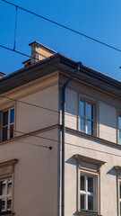 Corner of a house with windows and a downspout. The corner of the house is lit by the sun on one side and in the shade on the other.