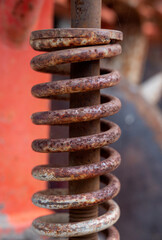 close-up shot reveals an old, rusted metal spring, its once-strong coils now weathered and textured by time, creating a rugged industrial beauty.