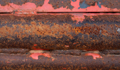The surface shows layers of aged, rusted metal with peeling orange paint, creating a rugged texture that tells a story of time, weather, and decay.