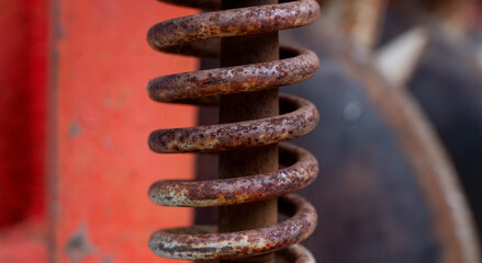 close-up shot reveals an old, rusted metal spring, its once-strong coils now weathered and textured...