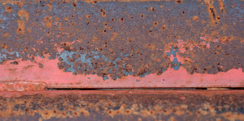 The surface shows layers of aged, rusted metal with peeling orange paint, creating a rugged texture that tells a story of time, weather, and decay.