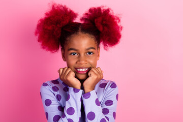 Young girl with pink hair smiles in purple polka dot shirt against pink background