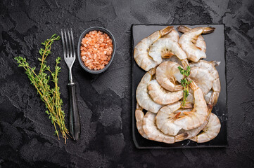 Raw headless white shrimps prawns on a marble board. Top view. Black background