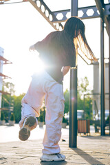 Young dancer showcases talent outdoors during sunset in urban park setting
