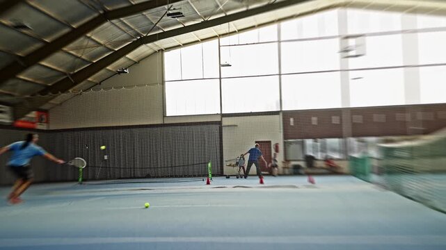 indoor tennis, male competitor delivering forceful serve during indoor training session, male tennis player fully extending racket overhead for serve amidst energetic indoor practice. Slow motion