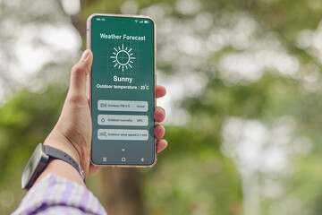 Naklejka premium A person checking the weather forecast on his smartphone. Sunny day.