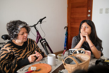 Mother and daughter are sitting at a table, one of them is wearing a striped shirt