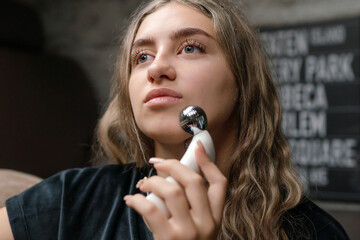 Youthful Lady Employs Skincare Device, Modern Individual Showcases Beauty Technology In Urban Setting