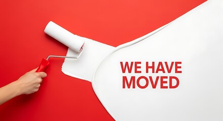 Hand painting a red wall white with a roller announcing we have moved