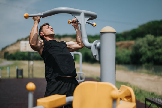 Individual performing strength training on a pull-up bar in a pleasant outdoor gym surrounded by lush greenery, showcasing fitness and healthy lifestyle in natural surroundings on a sunny day. - Powered by Adobe
