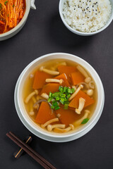 Clear mushroom and tofu soup topped with green onions. Light, healthy Asian dish photographed in a clean studio setting.