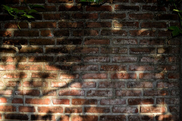 The shadows on the red brick wall are created by the midday sun.