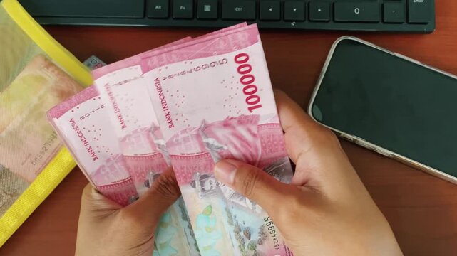 Close-up of female hands managing indonesian rupiah cash.